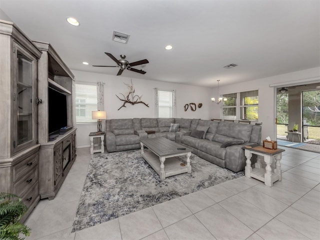 tiled living room featuring ceiling fan with notable chandelier