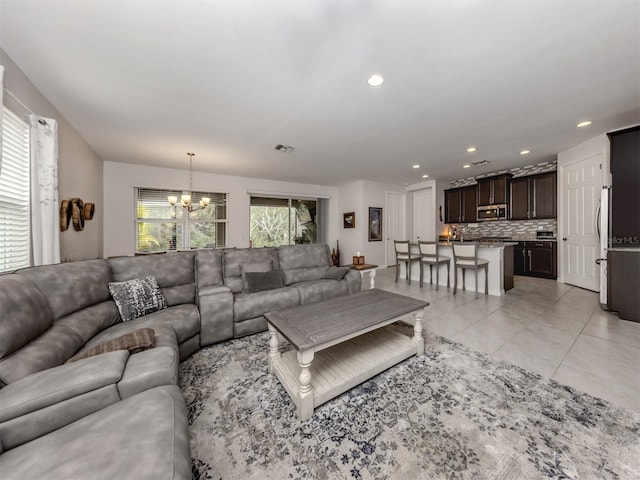 tiled living room with a healthy amount of sunlight and an inviting chandelier