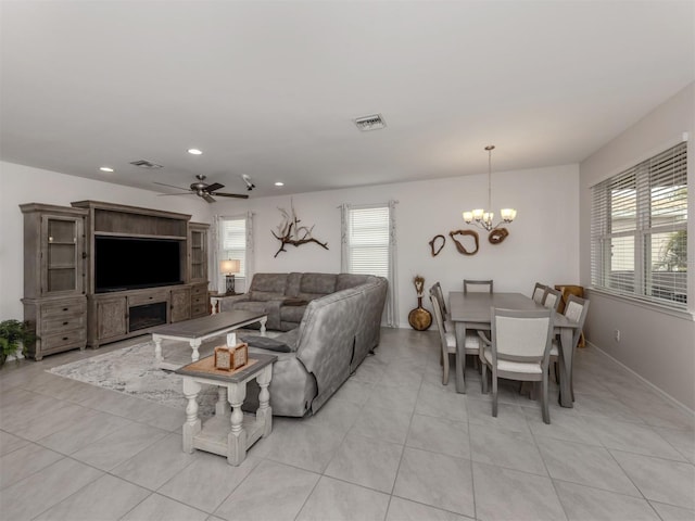 tiled living room featuring ceiling fan with notable chandelier