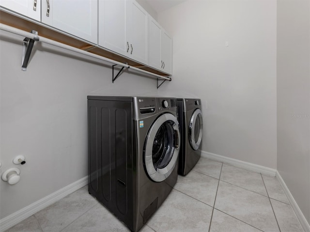 washroom featuring independent washer and dryer, cabinets, and light tile patterned flooring