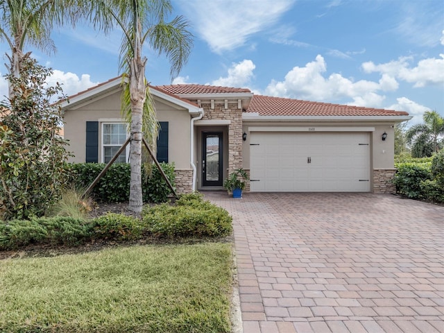 view of front of home with a tile roof, stone siding, a garage, stucco siding, and decorative driveway