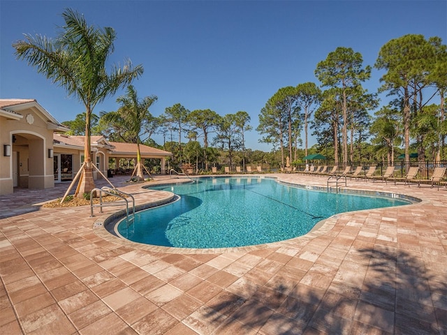 pool with a patio and fence