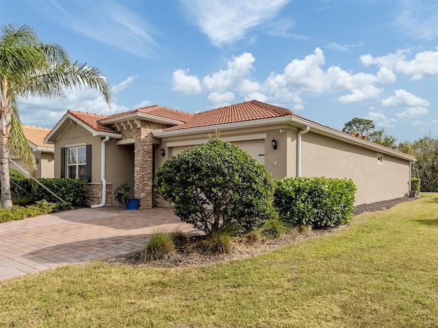 view of front of home featuring decorative driveway, a tiled roof, an attached garage, a front yard, and stucco siding