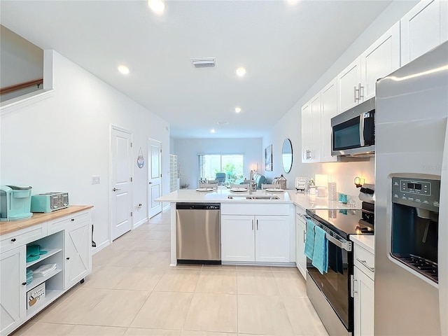 kitchen with kitchen peninsula, sink, white cabinets, and appliances with stainless steel finishes