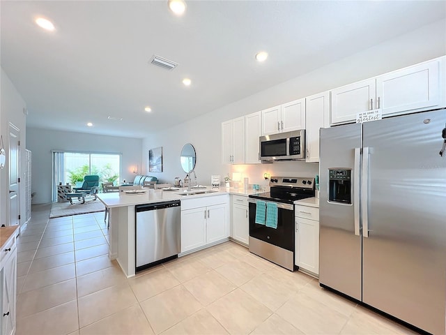 kitchen with kitchen peninsula, appliances with stainless steel finishes, white cabinets, and light tile patterned flooring