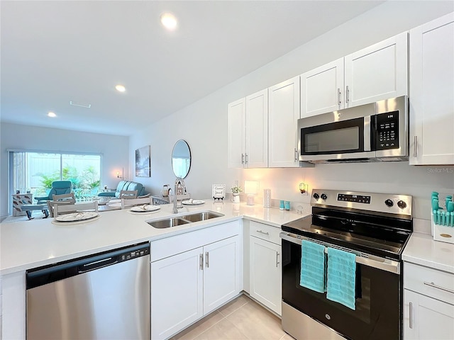 kitchen with light tile patterned flooring, kitchen peninsula, sink, and appliances with stainless steel finishes