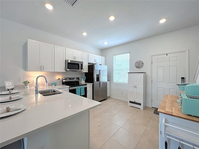 kitchen featuring kitchen peninsula, white cabinetry, sink, and appliances with stainless steel finishes