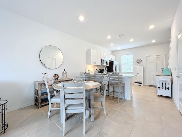 kitchen featuring a breakfast bar, light tile patterned floors, stainless steel appliances, and white cabinetry