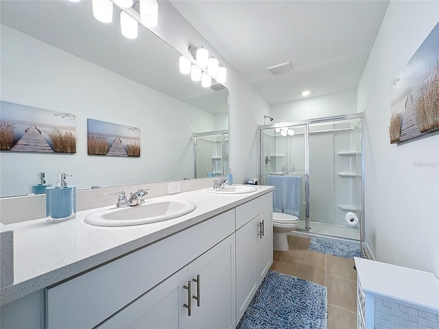 bathroom featuring tile patterned floors, vanity, toilet, and a shower with door