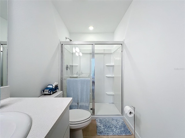 bathroom with tile patterned flooring, toilet, vanity, and walk in shower