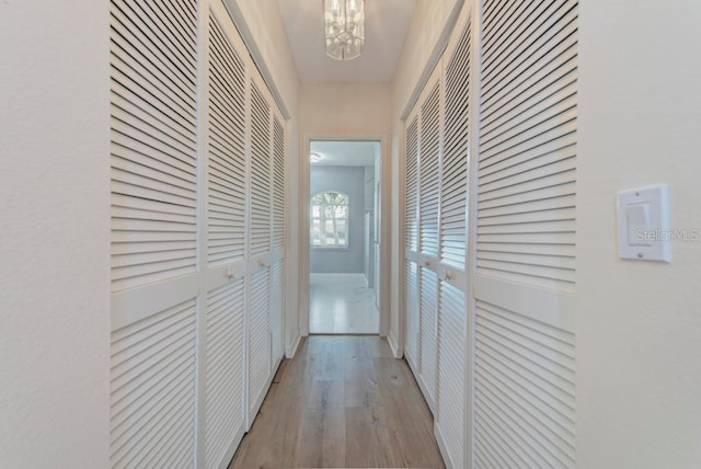 corridor with light hardwood / wood-style flooring and a chandelier