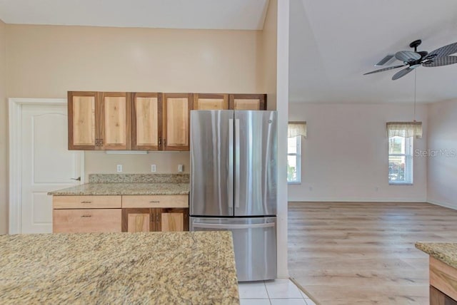 kitchen featuring light stone counters, stainless steel fridge, ceiling fan, and light hardwood / wood-style floors