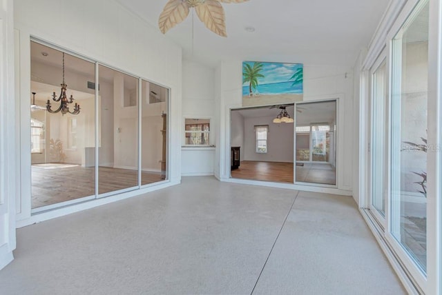 unfurnished sunroom with ceiling fan with notable chandelier