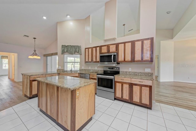 kitchen featuring stainless steel appliances, decorative light fixtures, light tile patterned floors, and kitchen peninsula