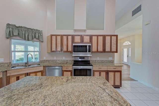 kitchen with light stone counters, sink, stainless steel appliances, and light tile patterned flooring