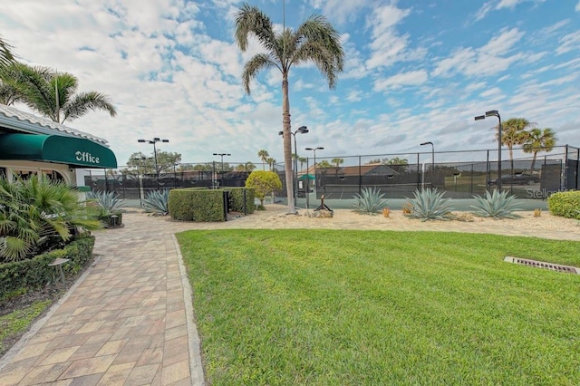 view of property's community featuring tennis court and a lawn