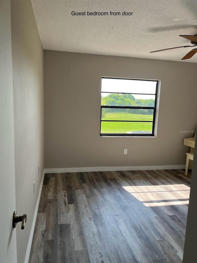 spare room with ceiling fan, dark wood-type flooring, and a textured ceiling