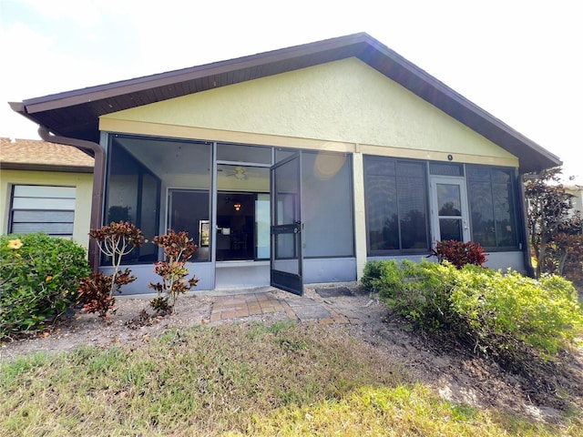 rear view of house with a sunroom and stucco siding