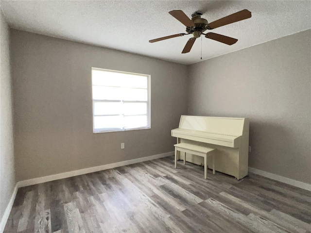 unfurnished room with a textured ceiling, baseboards, and wood finished floors