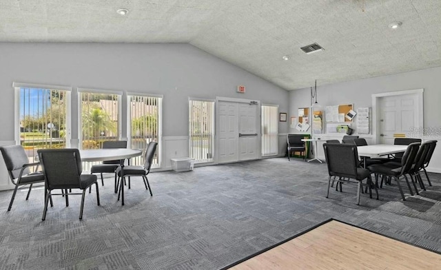 carpeted dining space with high vaulted ceiling and visible vents