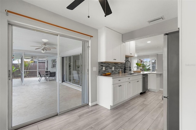 kitchen featuring stainless steel refrigerator, sink, light hardwood / wood-style flooring, decorative backsplash, and white cabinets