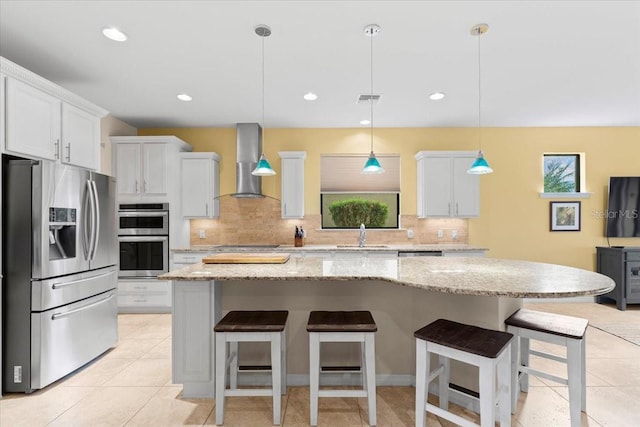 kitchen with pendant lighting, wall chimney exhaust hood, white cabinetry, and appliances with stainless steel finishes