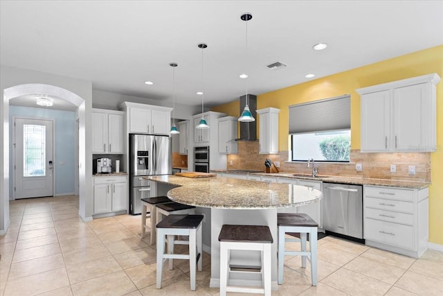 kitchen featuring sink, hanging light fixtures, a kitchen island, white cabinets, and appliances with stainless steel finishes