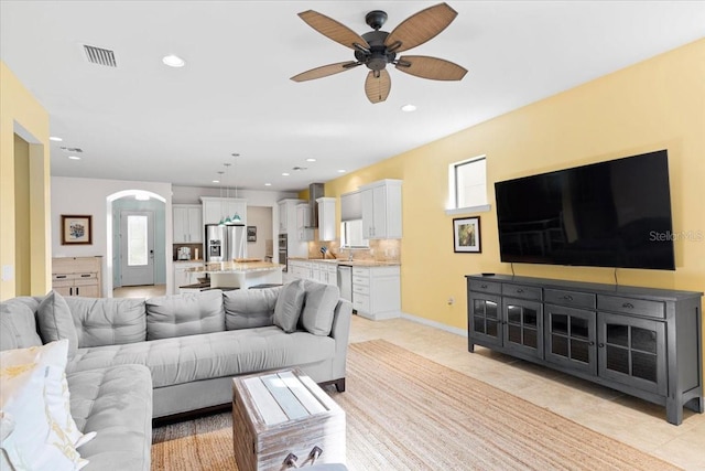 living room with ceiling fan, sink, light tile patterned flooring, and a healthy amount of sunlight