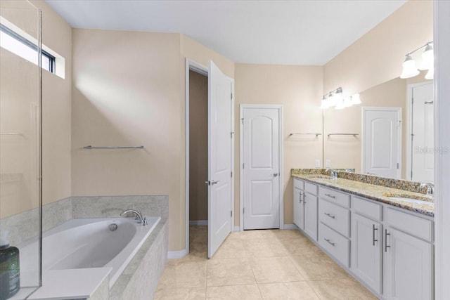 bathroom with tile patterned flooring, vanity, and a relaxing tiled tub