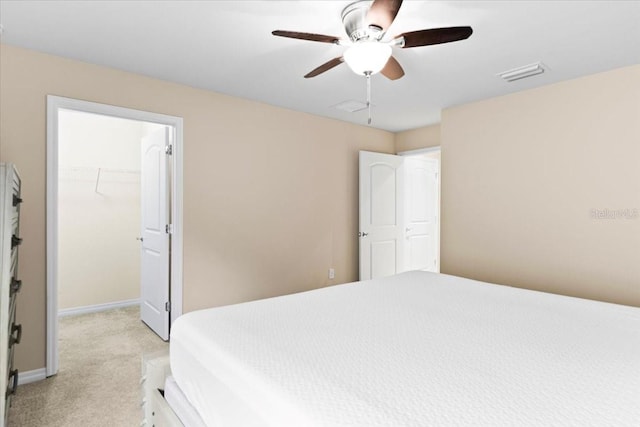 carpeted bedroom with a walk in closet, ceiling fan, and a closet