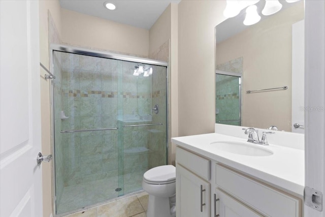 bathroom with tile patterned floors, vanity, a shower with shower door, and toilet