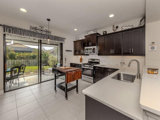 kitchen featuring decorative light fixtures, sink, dark brown cabinetry, stainless steel appliances, and light tile patterned floors