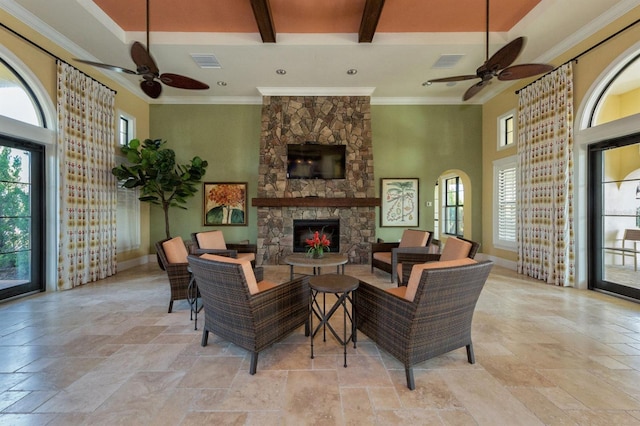 living room featuring ceiling fan, beam ceiling, a fireplace, and plenty of natural light