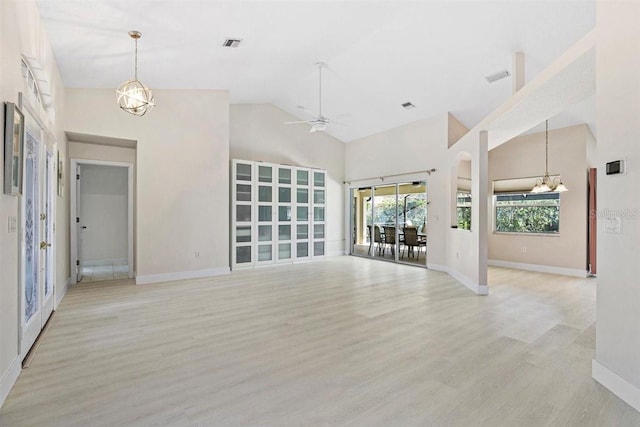 unfurnished living room with high vaulted ceiling, ceiling fan with notable chandelier, and light wood-type flooring