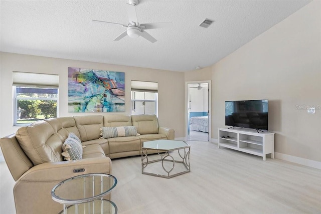 living room featuring ceiling fan, plenty of natural light, light hardwood / wood-style floors, and a textured ceiling