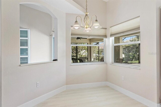 spare room with light hardwood / wood-style floors and ceiling fan with notable chandelier