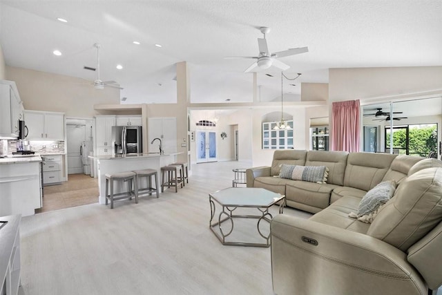 living room with sink, high vaulted ceiling, and a textured ceiling