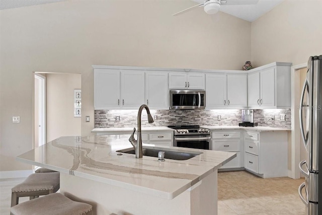 kitchen with high vaulted ceiling, a kitchen breakfast bar, sink, appliances with stainless steel finishes, and white cabinetry