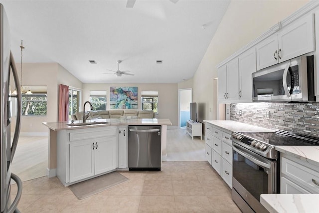 kitchen with appliances with stainless steel finishes, tasteful backsplash, sink, white cabinetry, and lofted ceiling