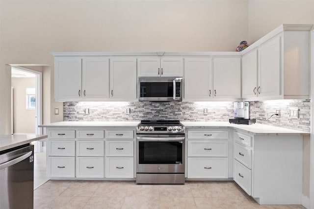 kitchen with decorative backsplash, light tile patterned floors, white cabinetry, and appliances with stainless steel finishes