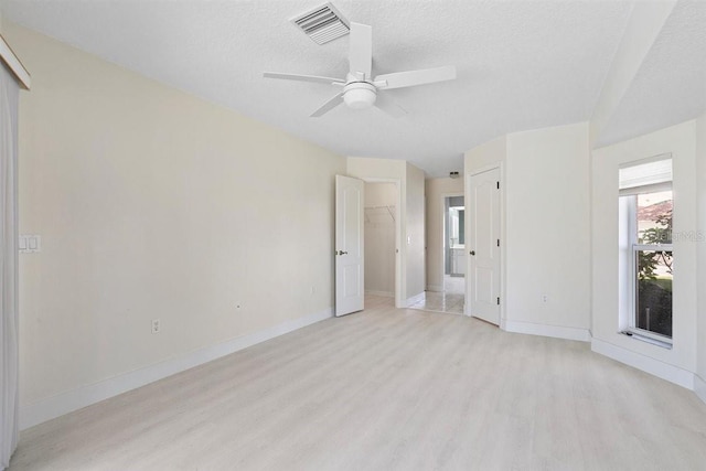 unfurnished room with a textured ceiling, light wood-type flooring, and ceiling fan