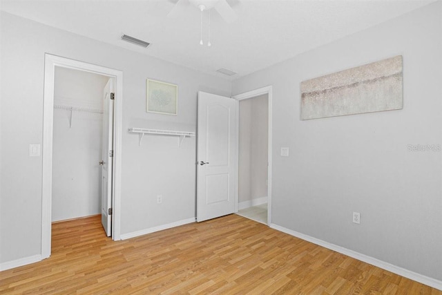 unfurnished bedroom featuring ceiling fan, a spacious closet, light hardwood / wood-style flooring, and a closet