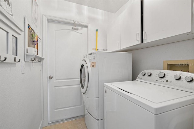 washroom featuring cabinets, light tile patterned floors, and washing machine and clothes dryer