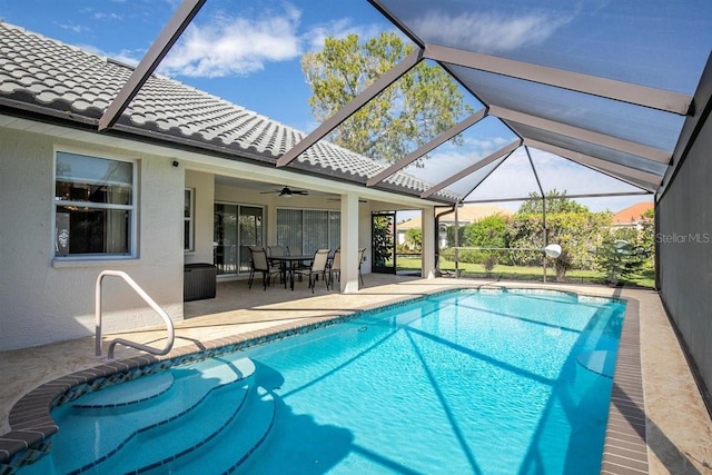 view of pool with a patio, glass enclosure, and ceiling fan