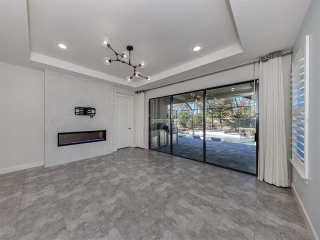 5733 Semolino St, Nokomis, FL 34275 - unfurnished living room with a tray ceiling, baseboards, a chandelier, a glass covered fireplace, and recessed lighting