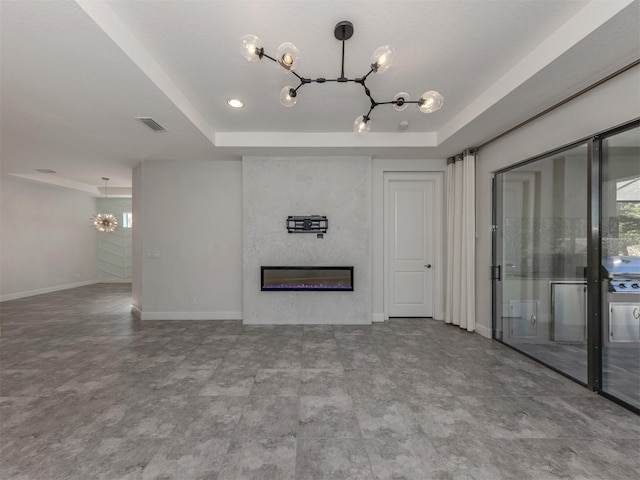 5733 Semolino St, Nokomis, FL 34275 - unfurnished living room with a chandelier, a tray ceiling, a fireplace, baseboards, and plenty of natural light