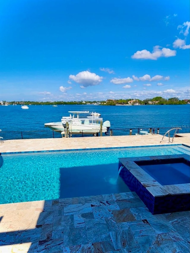 view of swimming pool with an in ground hot tub and a water view