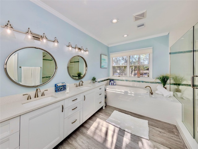 bathroom with tiled bath, wood-type flooring, vanity, and ornamental molding