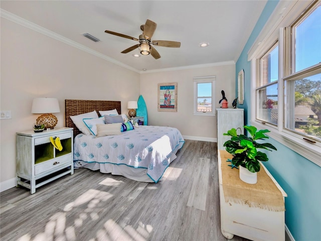 bedroom featuring ceiling fan, multiple windows, hardwood / wood-style flooring, and crown molding