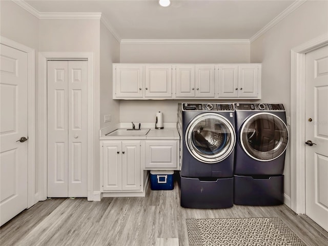 laundry room featuring sink, crown molding, light wood-type flooring, separate washer and dryer, and cabinets